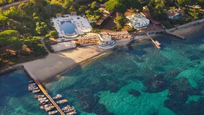 An aerial view of a coastal resort with a marina, a swimming pool, and beachfront villas. - COMO Le Beauvallon (Grimaud)