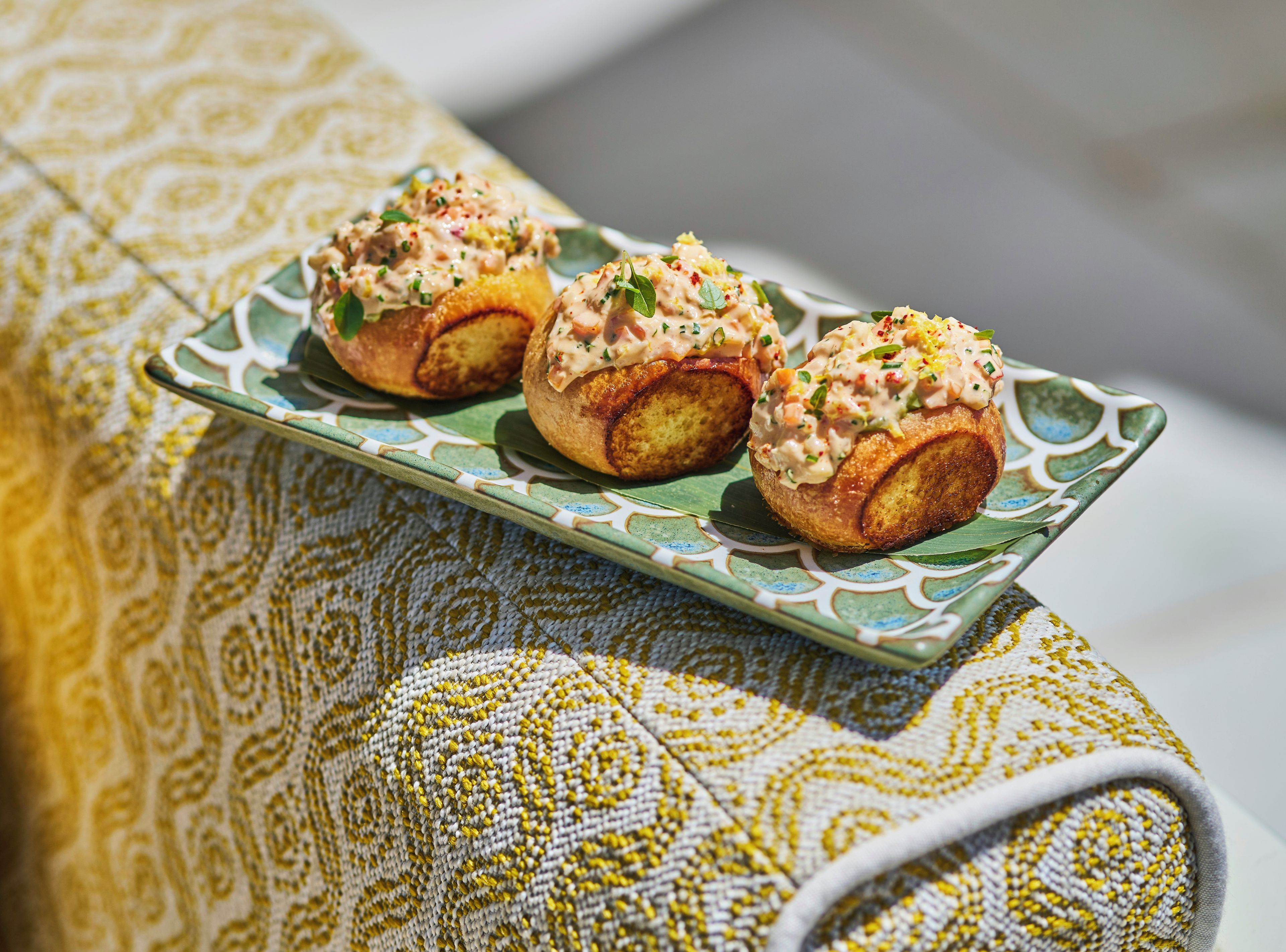 A plate with three pastries on a patterned tablecloth.