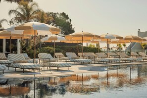 Un espace aménagé au bord de la piscine, avec des chaises longues et des parasols.