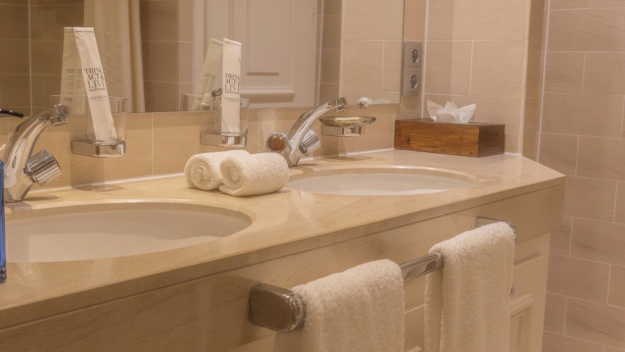 A bathroom with two sinks, a mirror, and a towel rack.