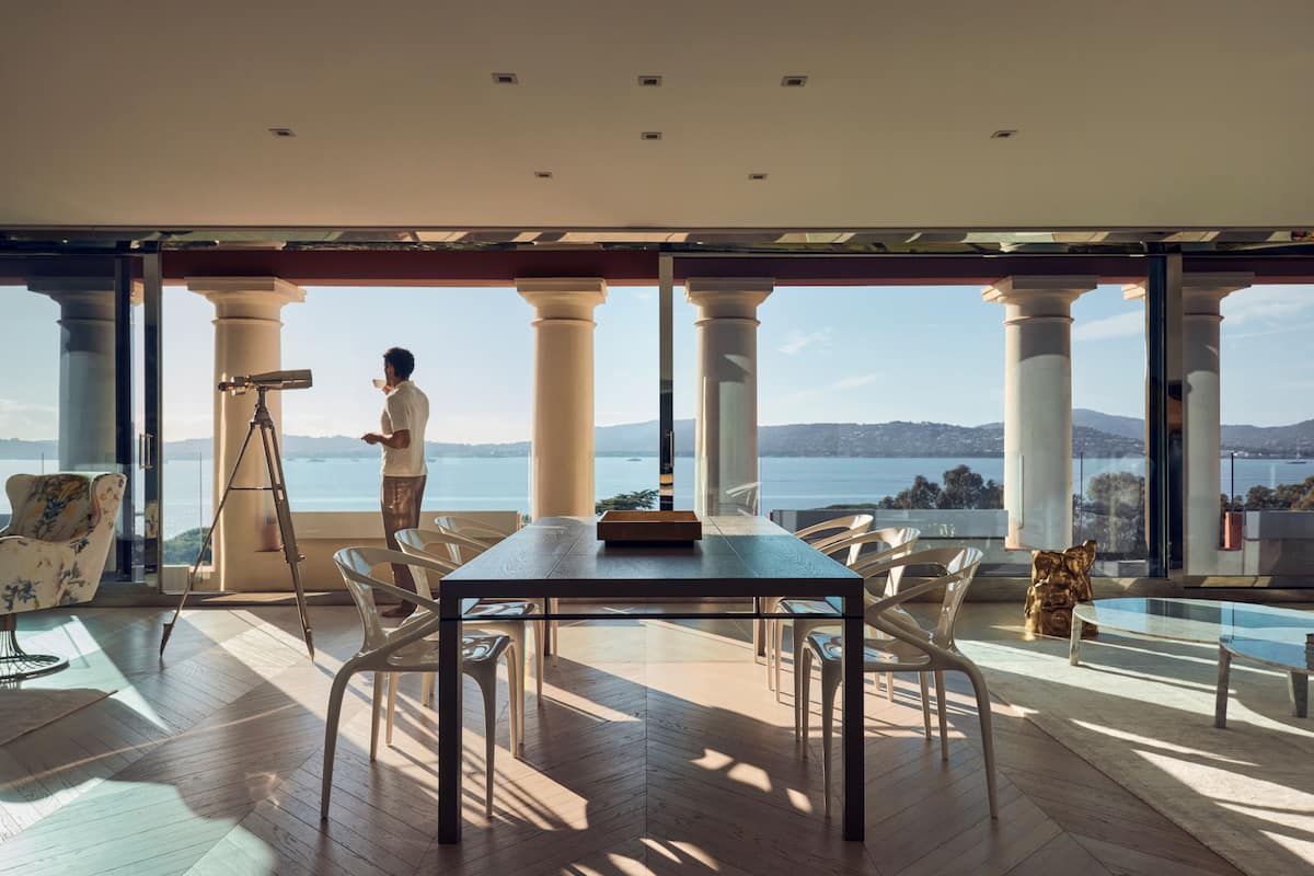 Un vaste espace dédié à la salle à manger, avec une grande table et des chaises, un télescope et une vue sur la mer.