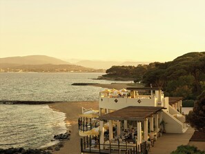 Un restaurante frente al mar con terraza al aire libre, una cubierta de madera y vistas a la costa.