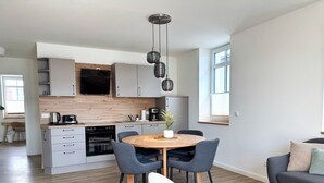 Une cuisine moderne dotée d’un îlot central, d’appareils électroménagers intégrés et d’un coin repas avec une table ronde et des chaises.