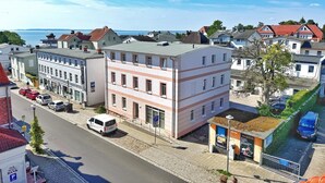A multi-story building with a flat roof, located in a town with a cobblestone street and parked cars. - Harbor master Gunnar - Family-friendly retreat with balcony (Sassnitz)