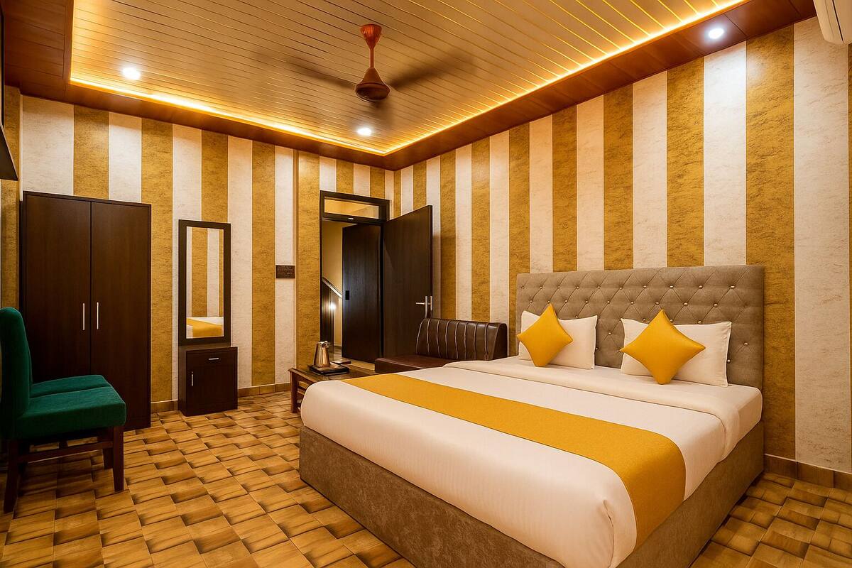 A hotel room with a large bed, a green chair, a wardrobe, and a mirror.