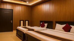 A hotel room with two beds, wooden paneling, and a dark door.