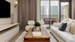 A modern living room with a wooden coffee table, white sofa, and a large TV on the wall.