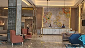 A modern hotel lobby with a reception desk, plush seating, and a decorative wall mural. - Siddharth The Fern An Ecotel Hotel Jalna (Jalna)