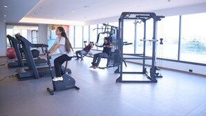A gym with cardio machines, weightlifting equipment, and large windows offering views of the city. - Siddharth The Fern An Ecotel Hotel Jalna (Jalna)