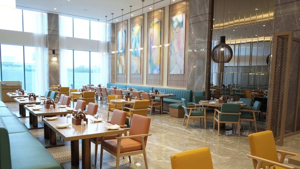 A spacious restaurant with high ceilings, large windows, and a variety of seating options including booths and tables. - Siddharth The Fern An Ecotel Hotel Jalna (Jalna)