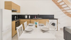 A modern kitchen with a dining area, including a table set for four, a microwave, stove, and washing machine.