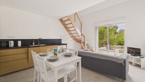A modern kitchen with a dining area, a staircase, and a large sliding glass door to the outdoors.