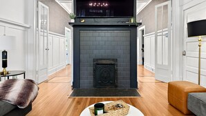 Ein modernes Wohnzimmer mit Kamin, Holzboden und einem darüber montierten Fernseher.