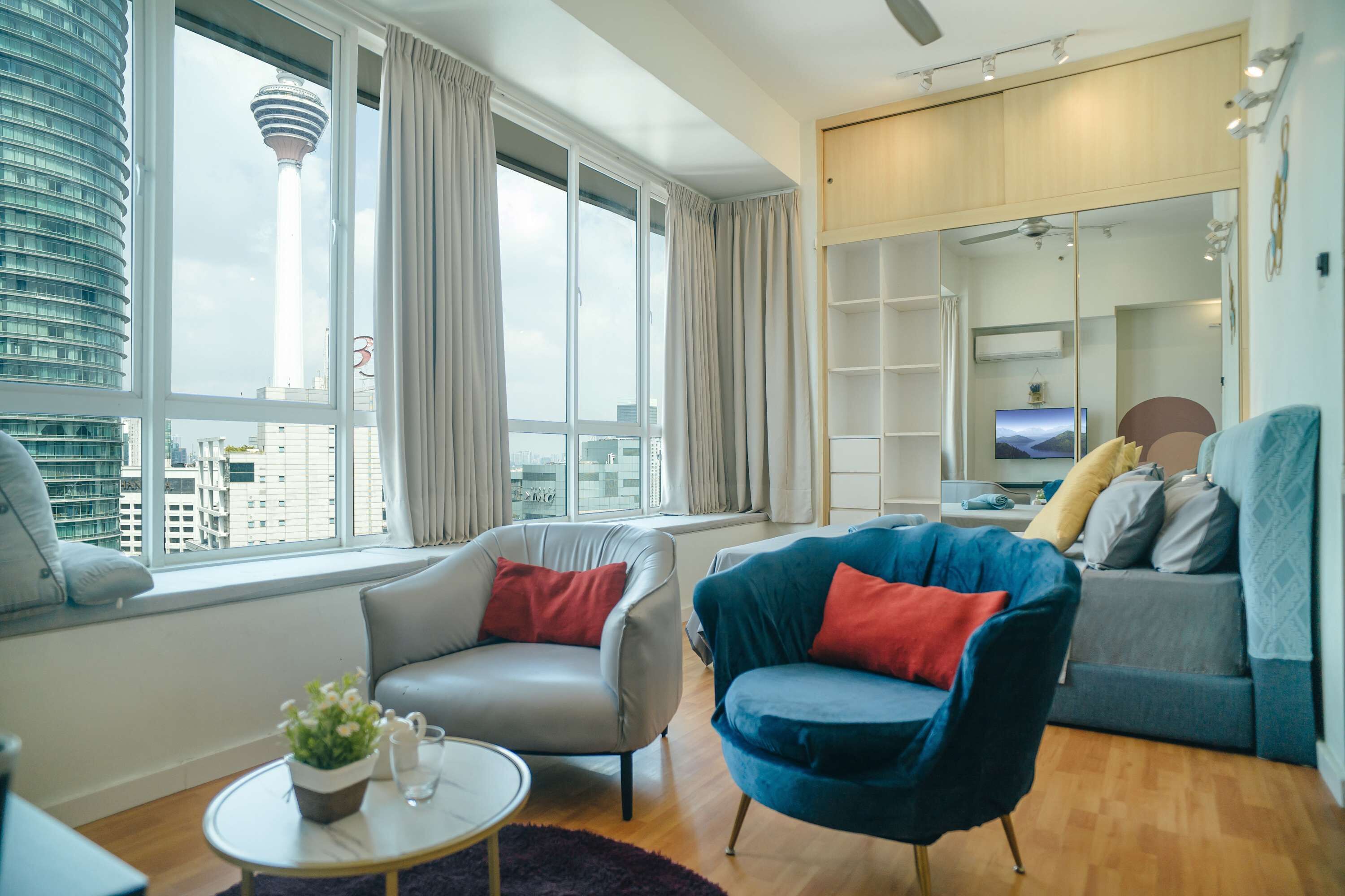 A modern living room with a large window, a sofa, a chair, and a television.