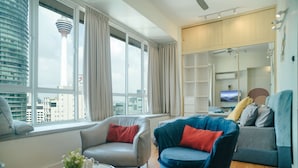 Un salon moderne avec une grande fenêtre, un canapé, un fauteuil et un téléviseur.