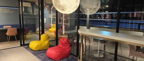 Interior moderno com divisória de vidro, uma mesa e poltronas de feijão.