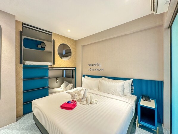 Una habitación de hotel moderna con una cama, un pequeño escritorio, una estantería con espejo y un espejo circular montado en la pared.