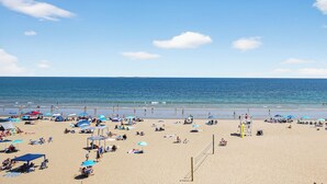 A beach with umbrellas, sun loungers, and a lifeguard tower.