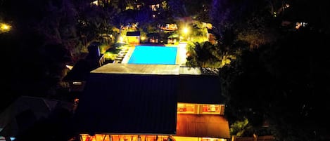 A hotel with a swimming pool, outdoor seating area, and a view of the surrounding landscape.