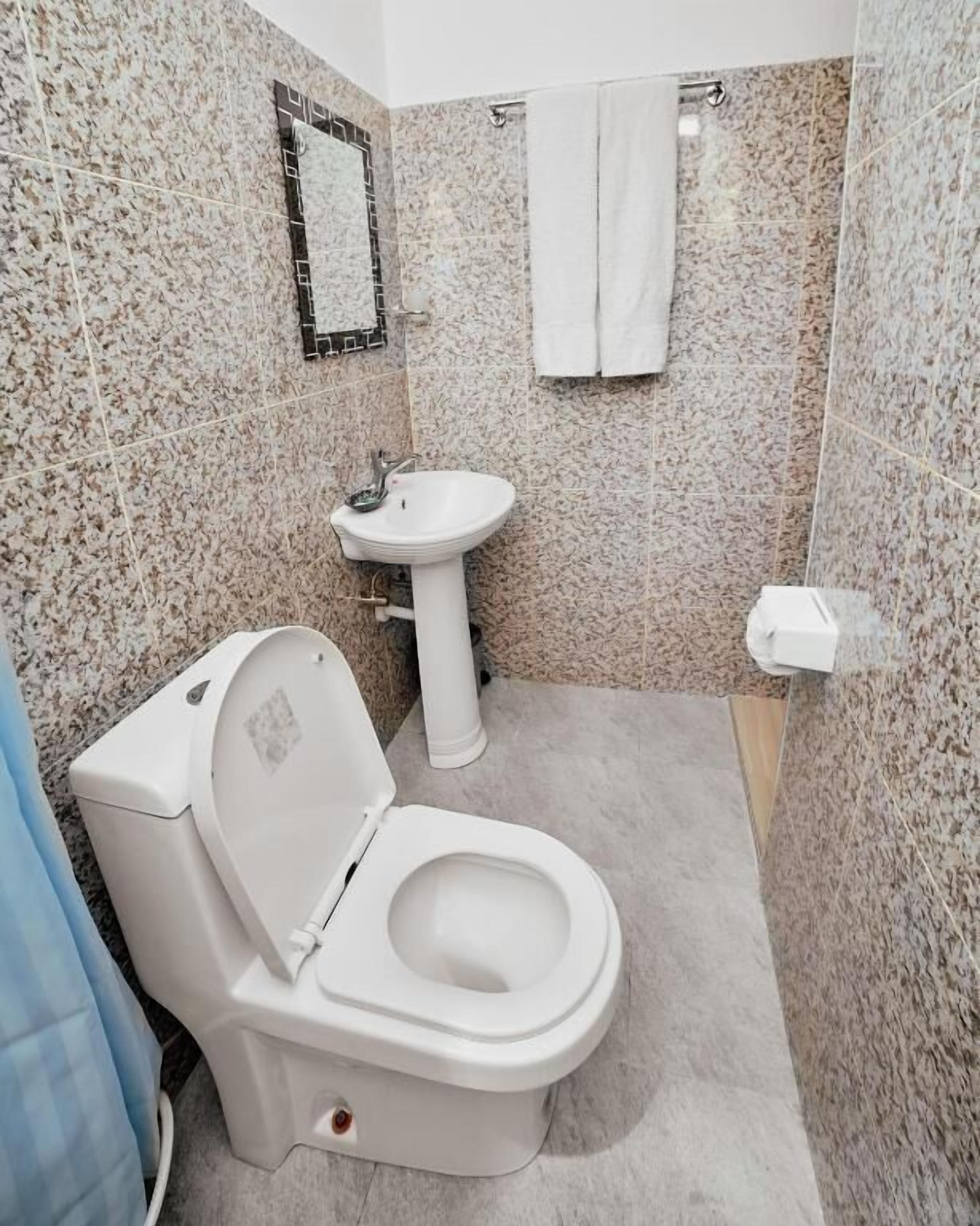 Ein Badezimmer mit Toilette, Waschbecken und Duschbereich.