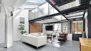 Un espace de vie moderne avec un canapé blanc, un mur en briques et une lucarne.