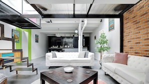 Un salon moderne avec un canapé blanc, une table basse en bois et un mur en briques.