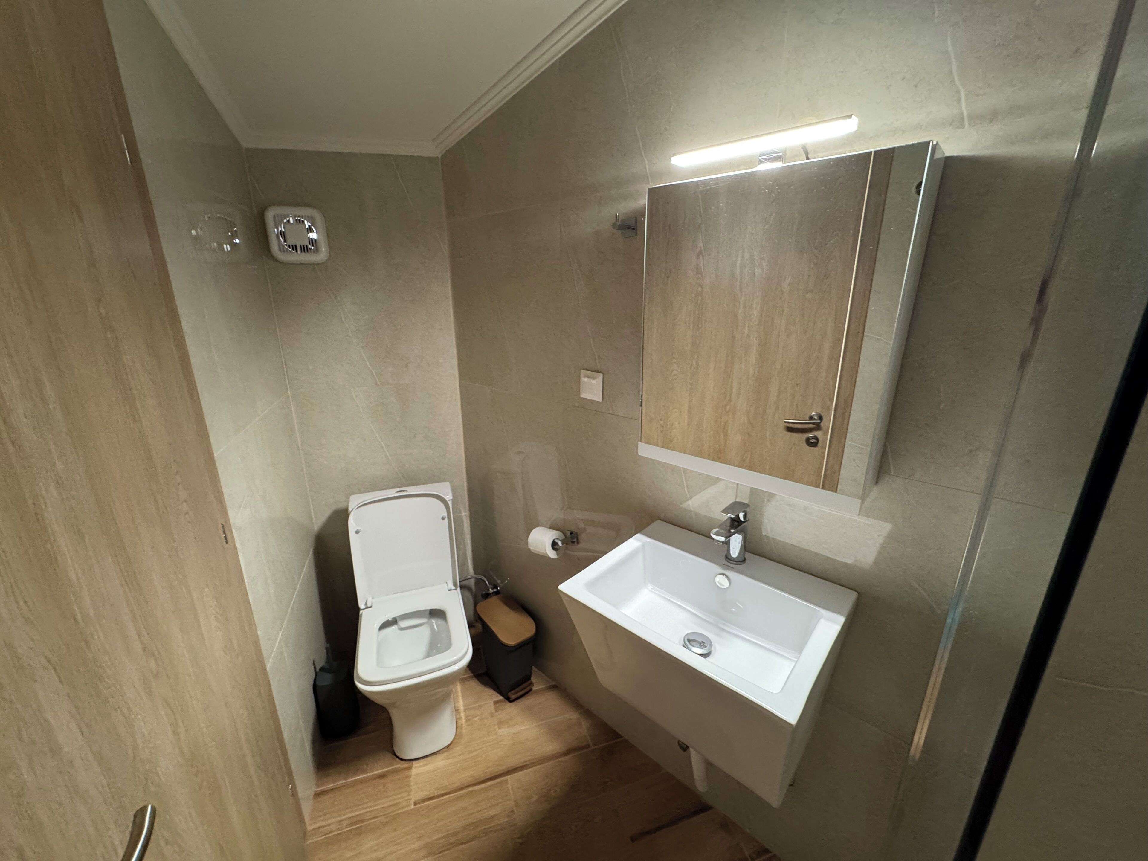 Une salle de bain équipée de toilettes, d’un lavabo, d’un miroir et d’un luminaire.