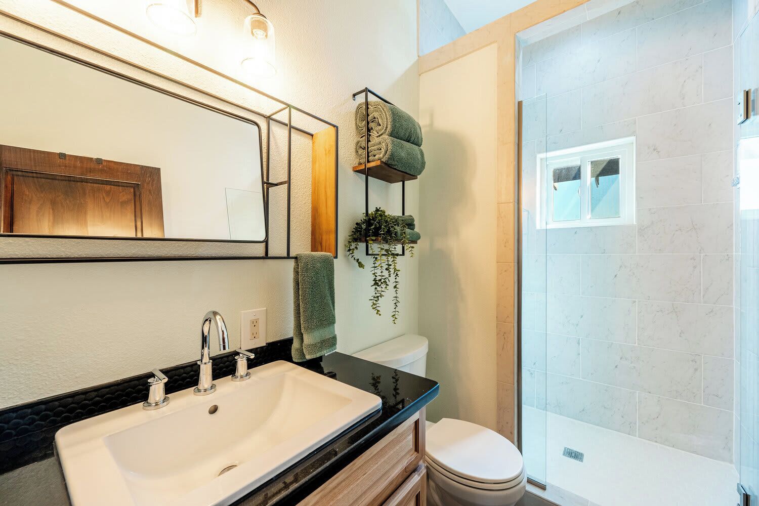 Une salle de bain moderne avec un grand miroir, un lavabo, des toilettes et un espace douche.