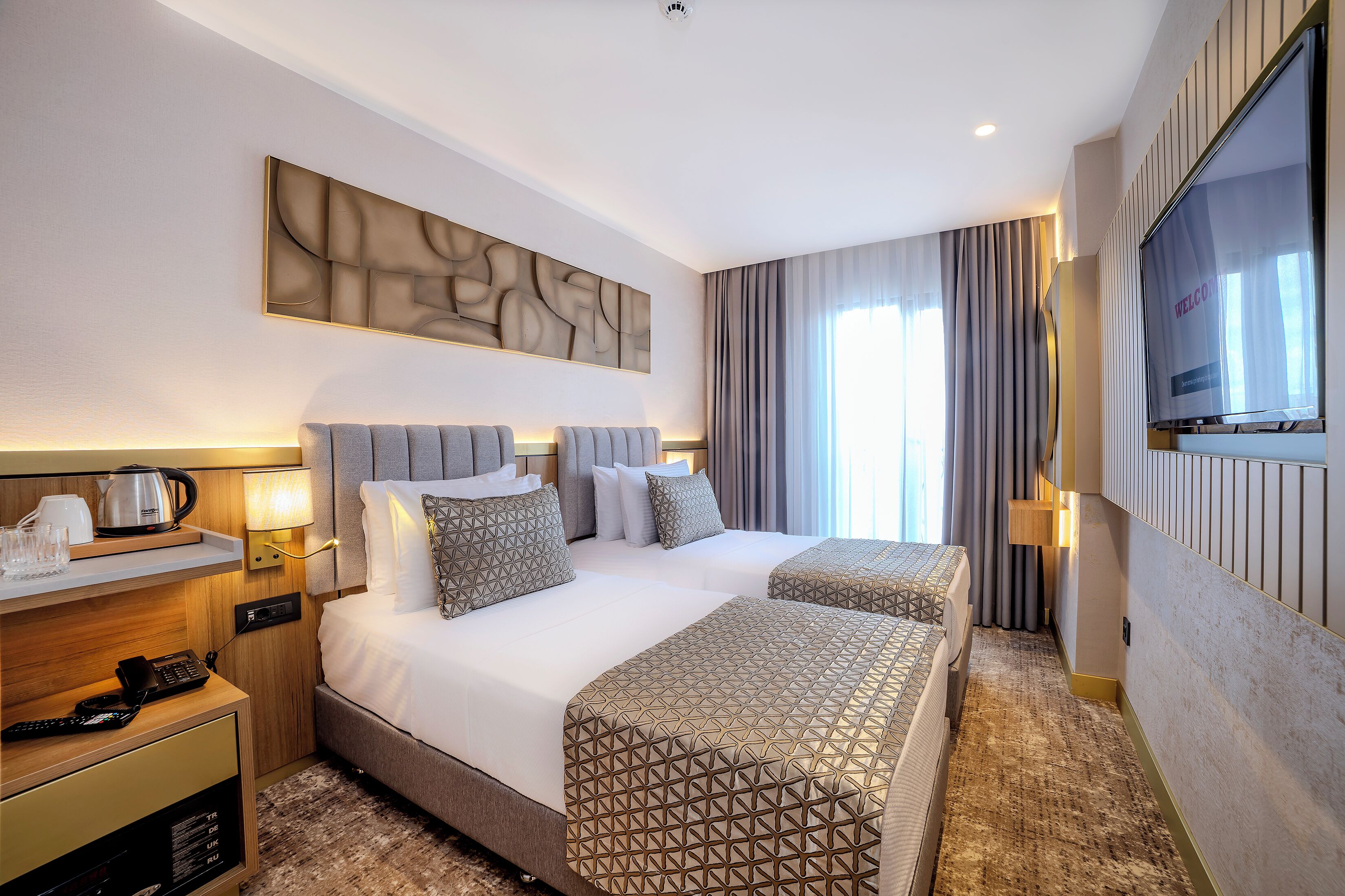 A hotel room with a large bed, bedside tables, a flat-screen TV, and a decorative wall piece.