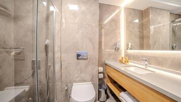 A modern bathroom with a glass-enclosed shower, a white toilet, and a wooden vanity with a sink.