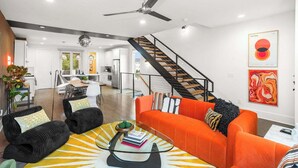 Una sala de estar moderna con una escalera, un comedor y una cocina al fondo.