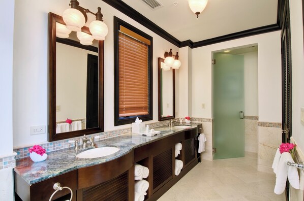 A bathroom with a double sink vanity, large mirrors, and a green door.