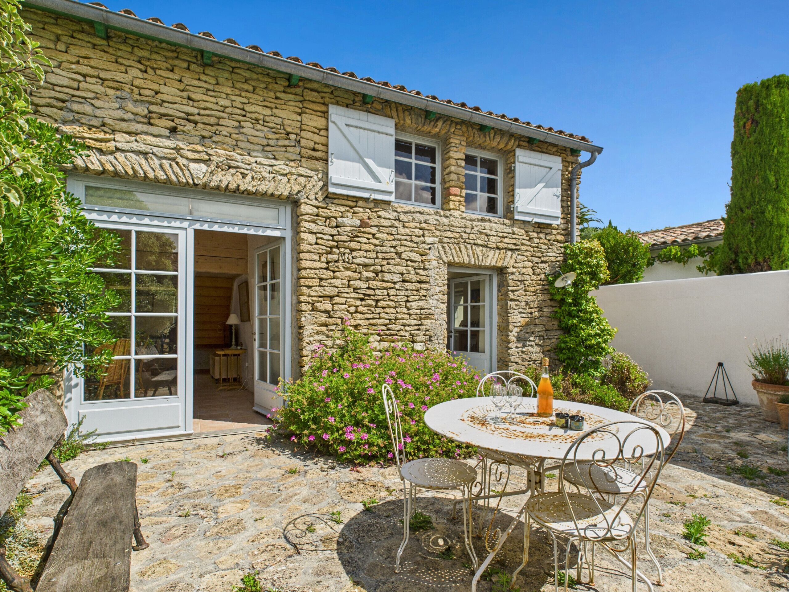 Una casa de piedra con un patio, mobiliario exterior y un jardín.