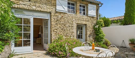Una casa de piedra con un patio, mobiliario exterior y un jardín.