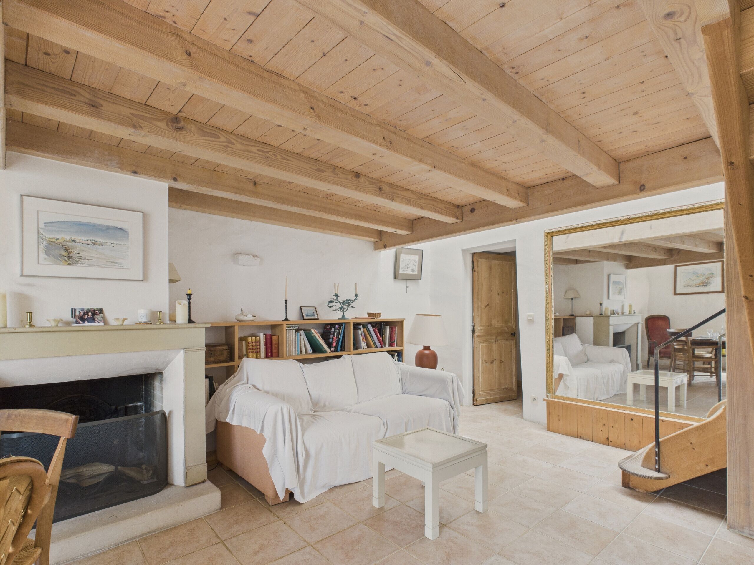 A cozy living room with a fireplace, a sofa, a coffee table, and a bookshelf.