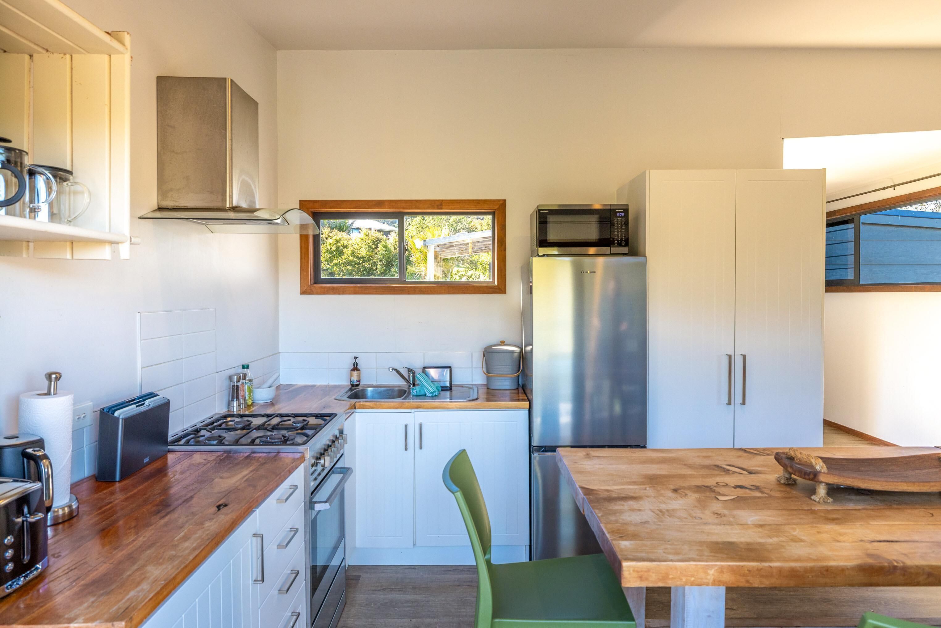 Een moderne keuken met een houten aanrecht, roestvrijstalen apparatuur en een raam dat voor natuurlijk licht zorgt.