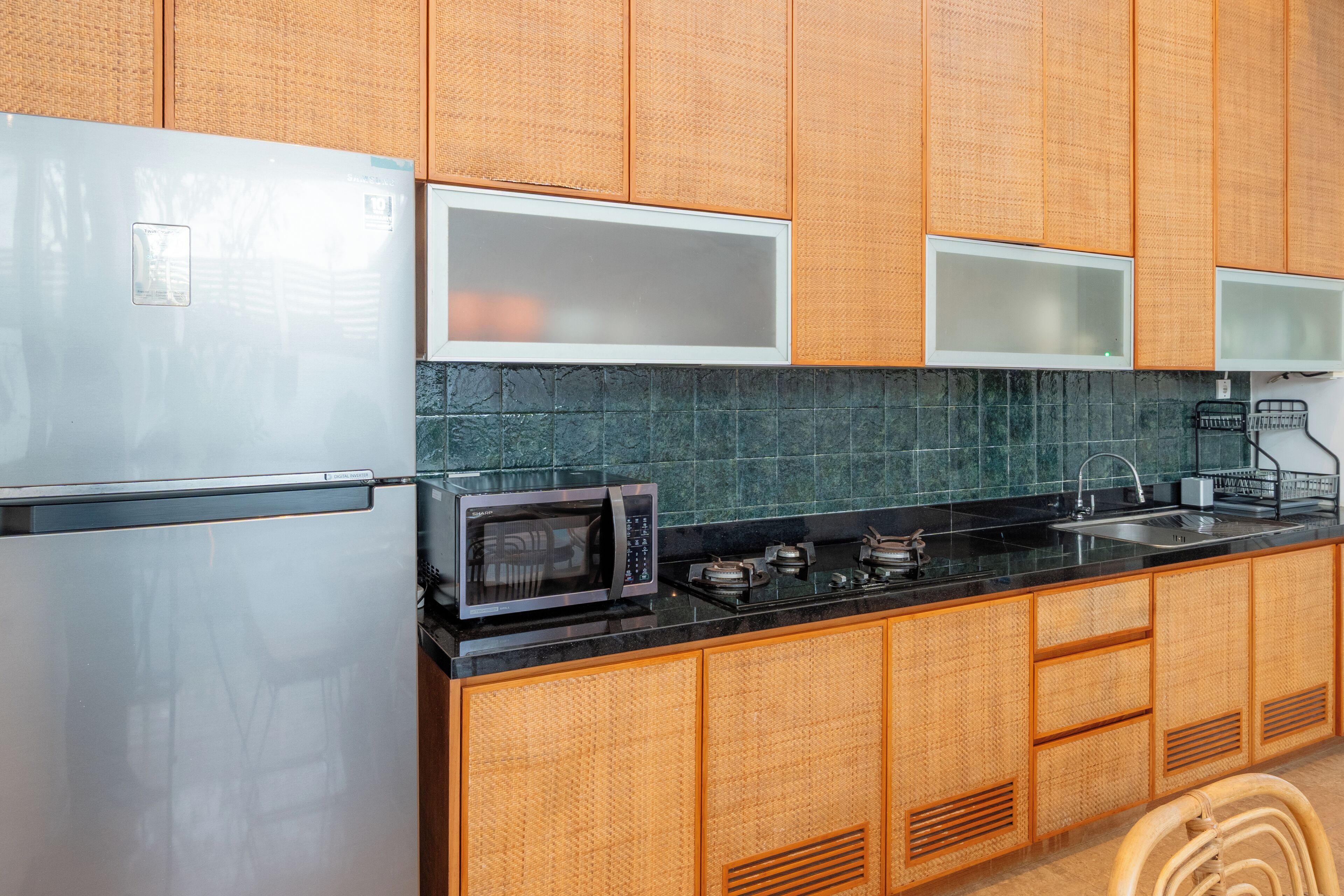 A kitchen with a refrigerator, microwave, stove, sink, and wooden cabinets.