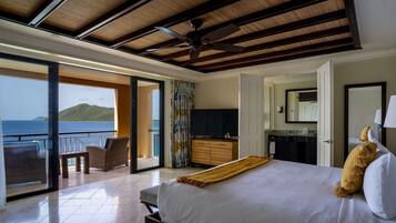 A spacious bedroom with a large bed, a balcony with a view of the sea, and a modern bathroom.