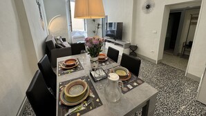 A dining area with a table set for four, a television, and a decorative wall piece. - Nice apartment for 5 guests with WIFI, A/C and TV (Lucca)