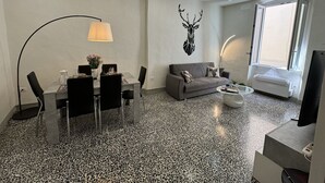 A modern living room with a dining area, a grey sofa, a coffee table, and a wall-mounted deer head decoration. - Nice apartment for 5 guests with WIFI, A/C and TV (Lucca)