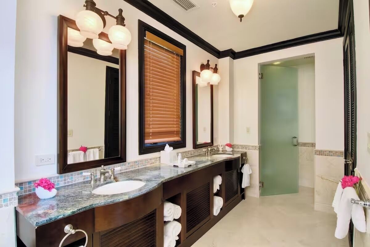 A bathroom with two sinks, large mirrors, and a shower area.