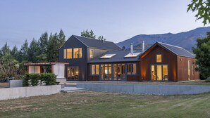 A modern two-story house with large windows and a covered patio.