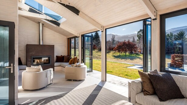 A modern living room with a fireplace, comfortable seating, and large windows offering a view of the outdoors.