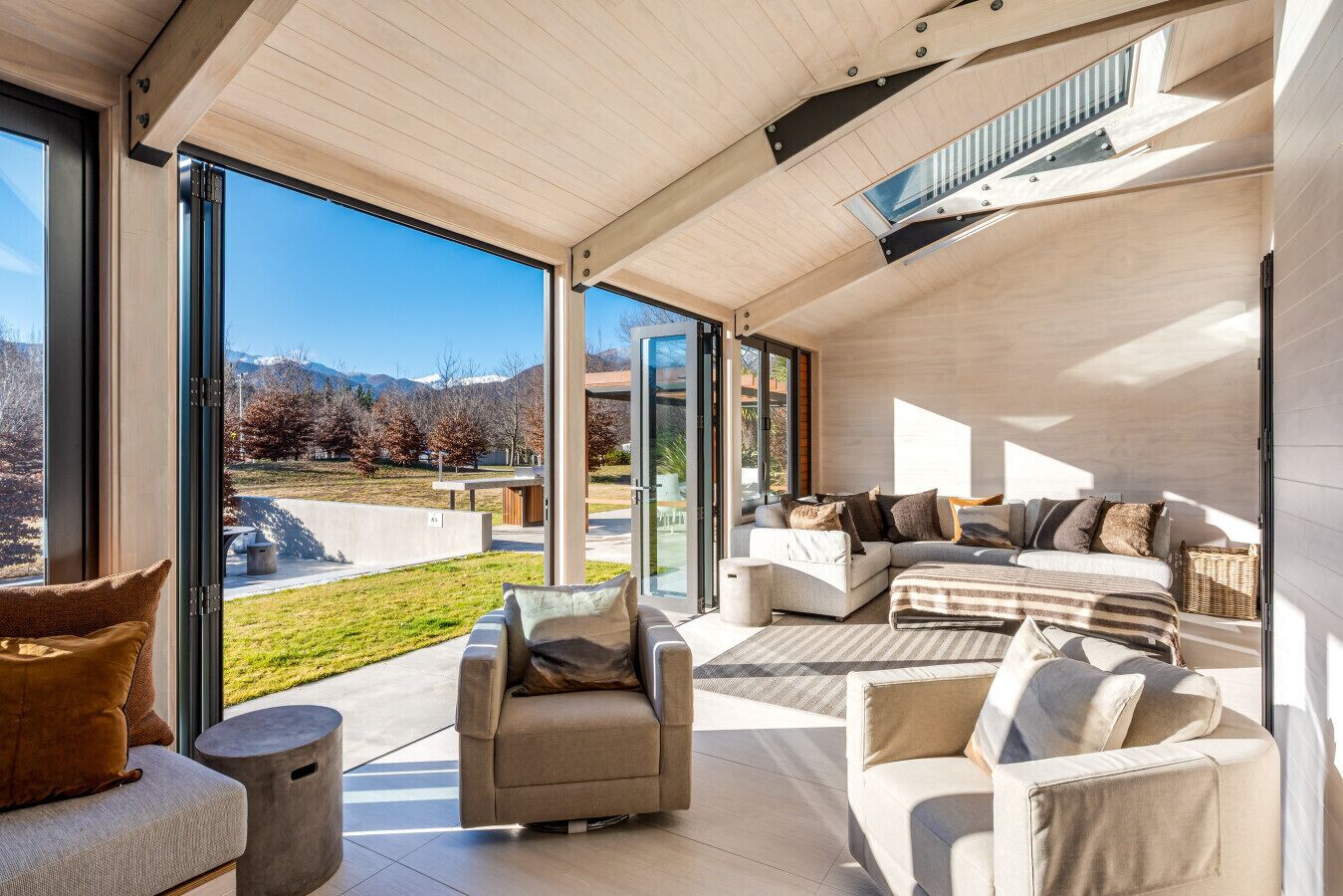 A modern living room with a large sliding glass door leading to a balcony, offering a view of a mountainous landscape.