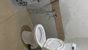 A bathroom with a white toilet, a shower, and a sink. - Hotel RR Inn (Vadodara)
