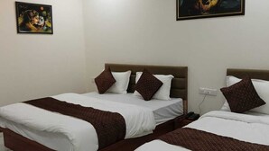 A hotel room with two beds, a ceiling fan, an air conditioning unit, and two paintings on the walls. - Hotel RR Inn (Vadodara)