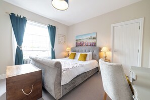 Een slaapkamer met een bed, bedlampen, een houten kist, een stoel en een deur.