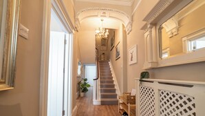 Ein Flur mit Holzboden, einer Treppe und einer verzierten Decke.