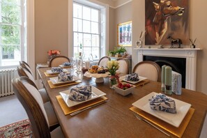 Een eetkamer met een lange tafel gedekt voor een maaltijd, met verschillende gerechten en decoraties.