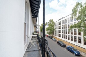 Een balkon met uitzicht op geparkeerde auto's en een gebouw met grote ramen.